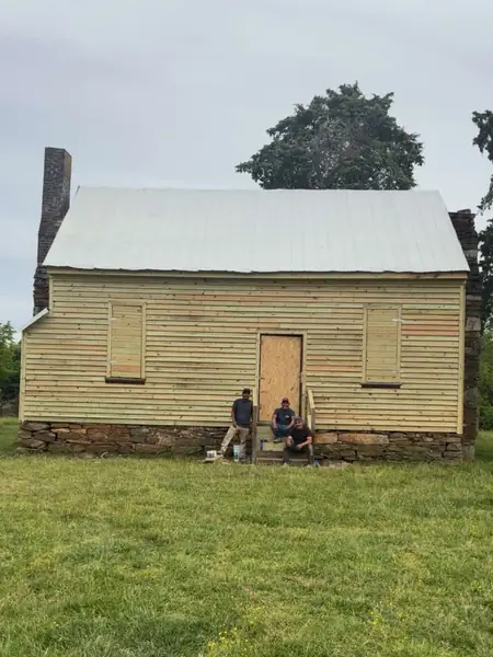 The same farmhouse after restoration with new wood siding, door and steps